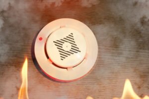 Smoke detector activated by smoke and flames during a potential fire emergency.